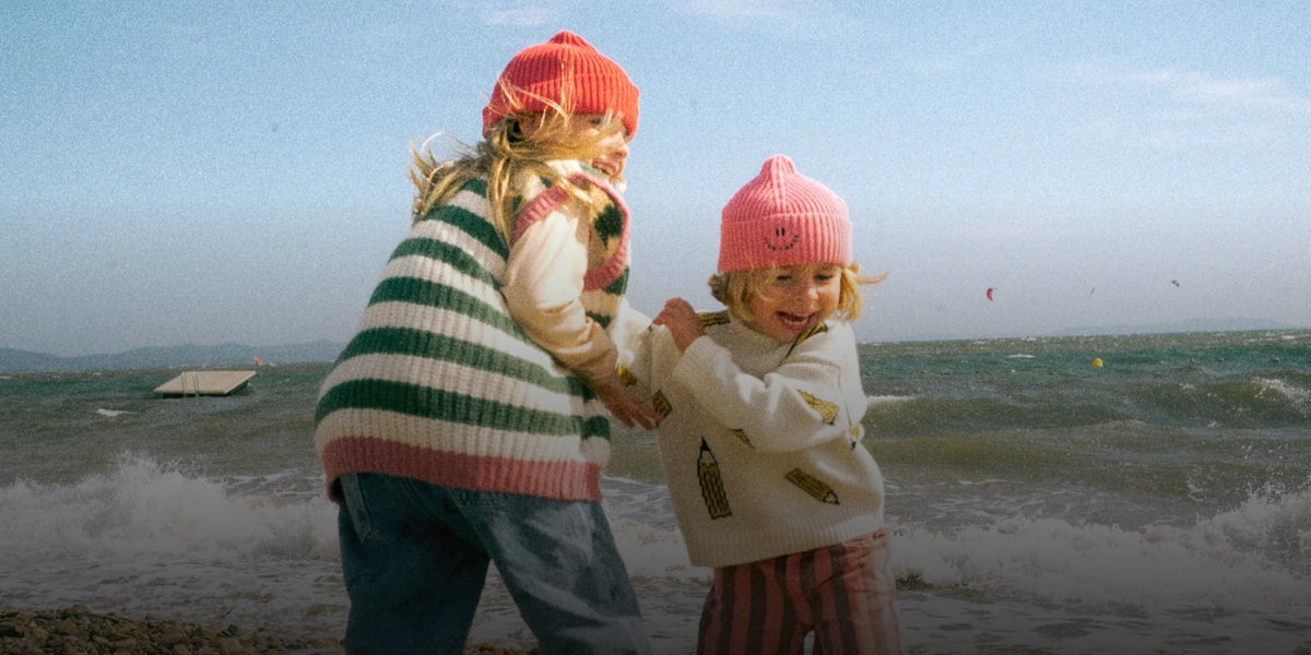 Zwei Kinder in Strickmützen am Strand